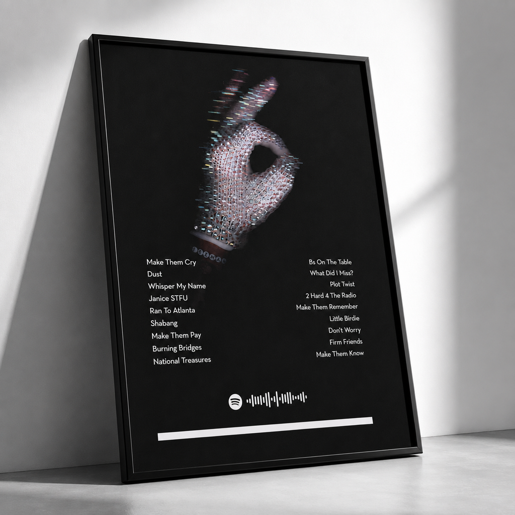 A framed Spotify songlist art print leaning against a white wall. The print features a black background with a rhinestone-embellished hand gesture and lists of song titles in white text.