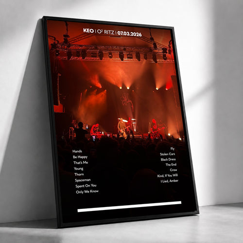 A framed custom photo print leaning against a white wall. The print shows a concert stage scene with orange stage lighting and black text at the top reading 'KEO O2 RITZ'.