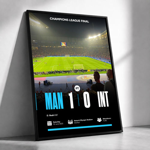 A framed vertical poster leaning against a white wall, showing a Champions League final match scene with a green stadium field, crowd, and large score text reading MAN 1 0 INT.