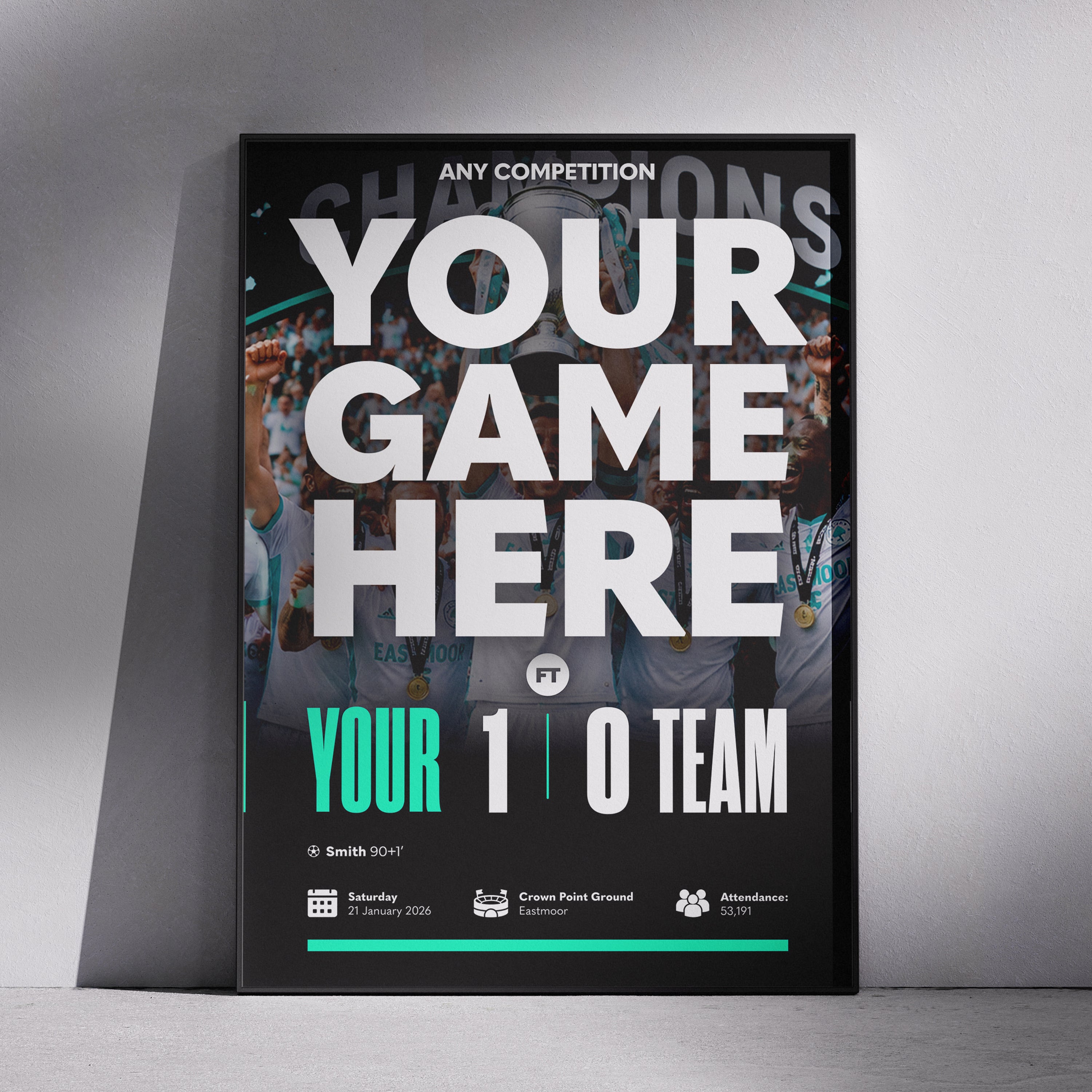 A framed sports event poster mockup leaning against a gray wall on a concrete floor. The poster features a black background with a blurred crowd photo, large white text reading 'YOUR GAME HERE', and teal accents including 'YOUR 1 0 TEAM'.