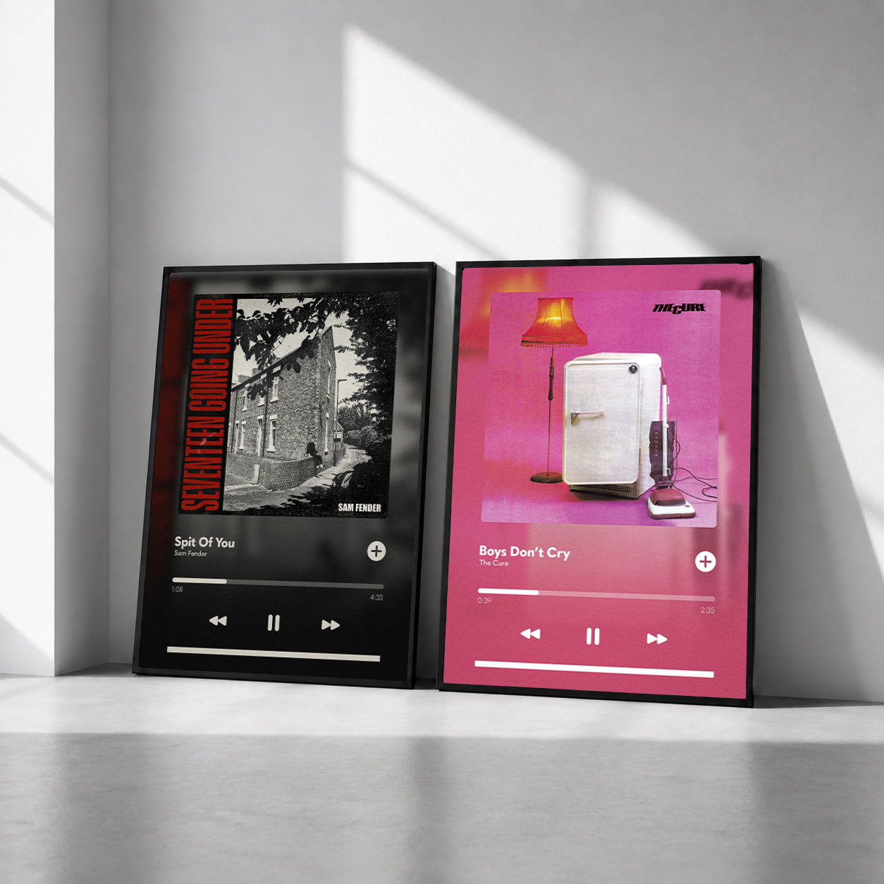 Two framed music player wall art prints leaning against a gray wall on a concrete floor, with dramatic window light casting shadows across the scene.